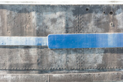 <b>BLEU</b> | Flanc d'une vieille péniche, la lumière rasante met esthétiquement en valeur les lignes de rivets